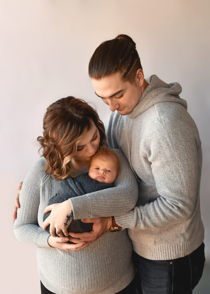 studio newborn session, family of 3, mom kissing baby on head