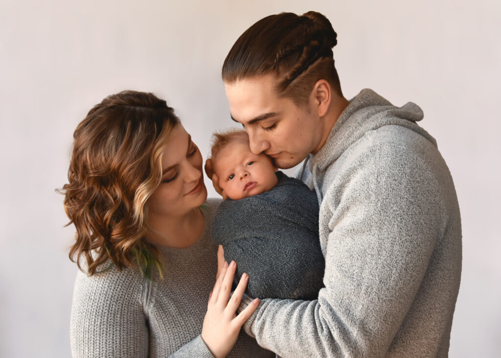 studio newborn session, mom and dad holding baby close