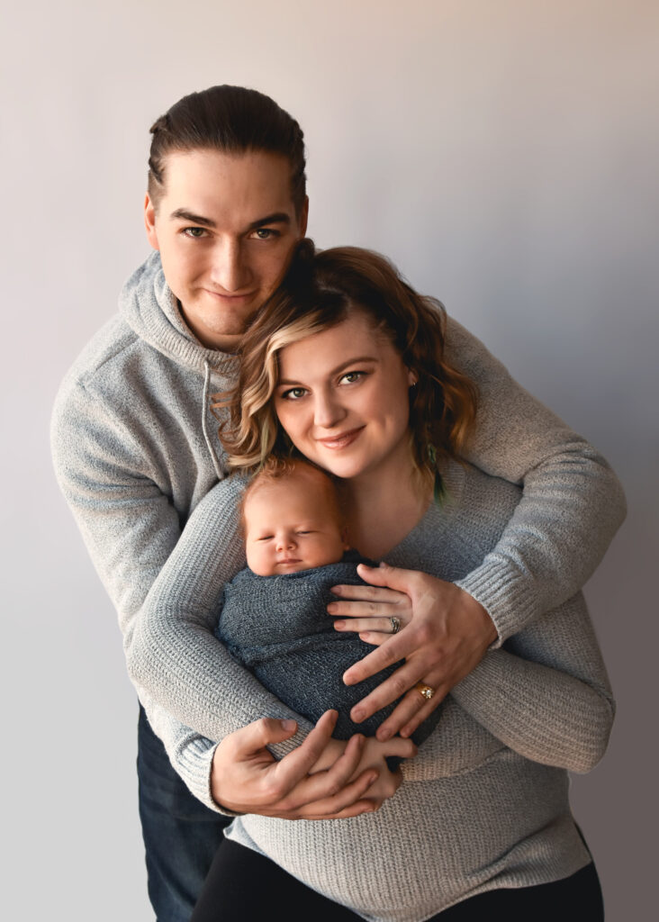 studio newborn session, dad holding mom and baby smiling