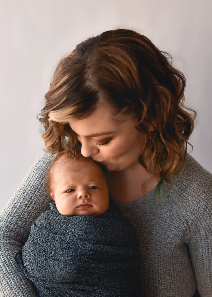 studio newborn session, mom kissing baby who has eyes open