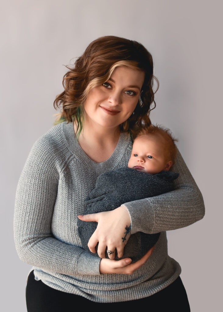 studio newborn session, mom sitting holding baby