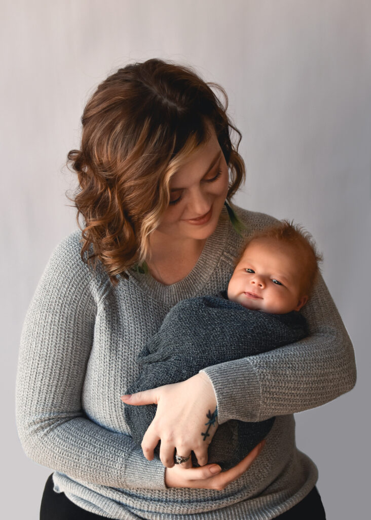 studio newborn session, mom looking at grinning baby