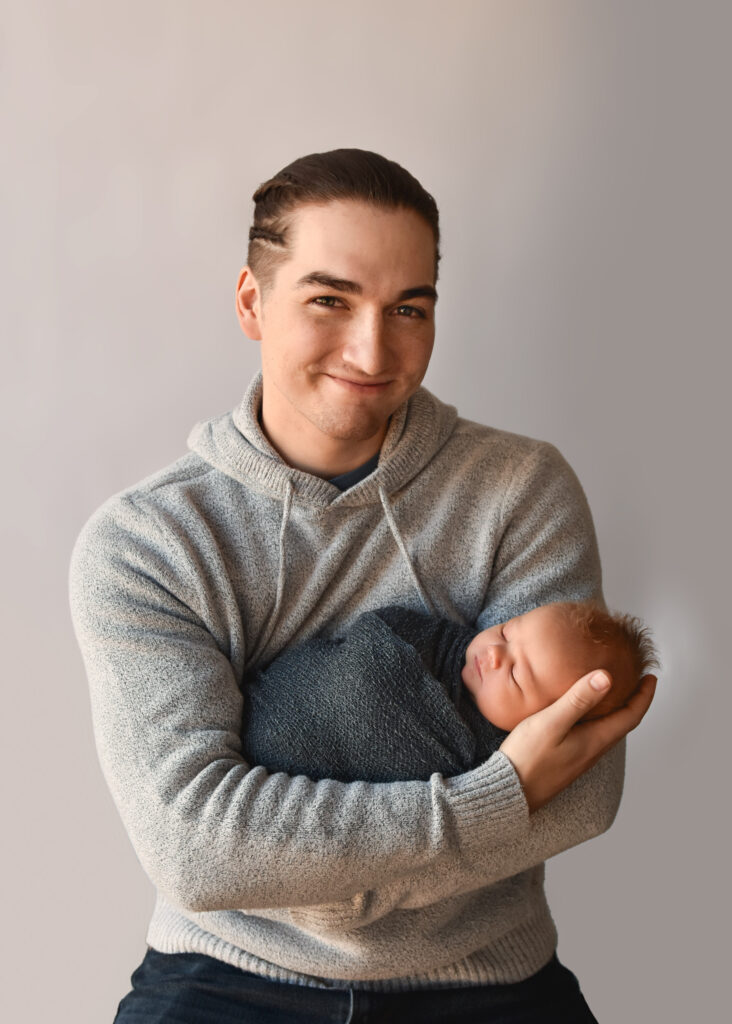 studio newborn session, dad smiling and holding baby boy