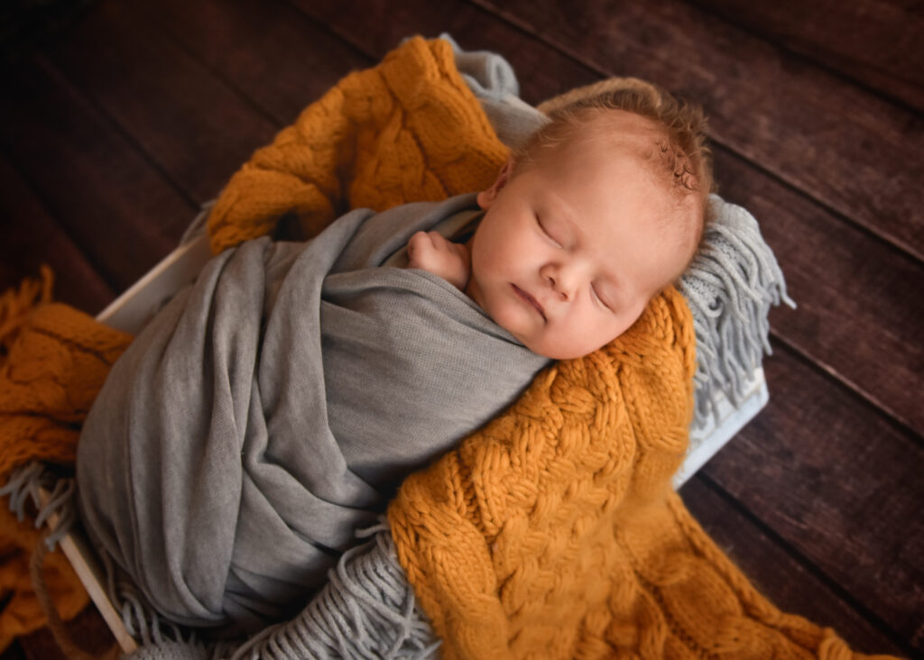 studio newborn session, baby wrapped in grey with yellow blanket