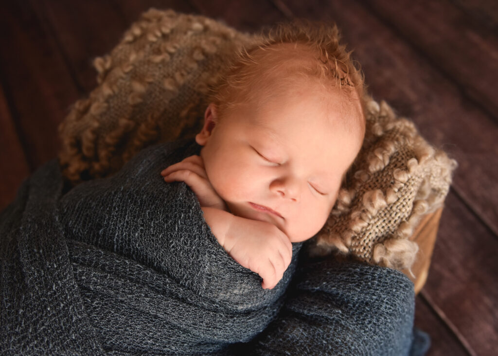 baby in blue wrap with hands crossed